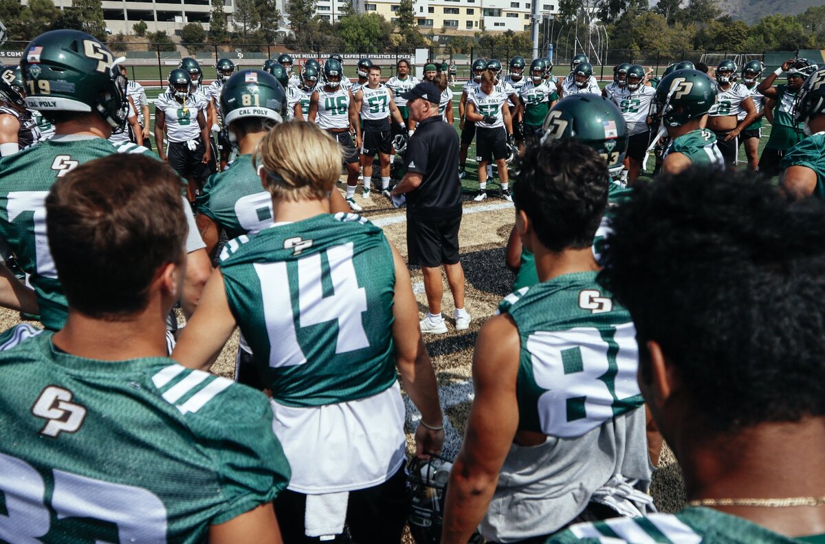 The Cal Poly football team gathers around Head Coach Tim Walsh at the start of its final practice of fall camp at Doerr Family Field in 2018. Walsh announced his retirement in November.