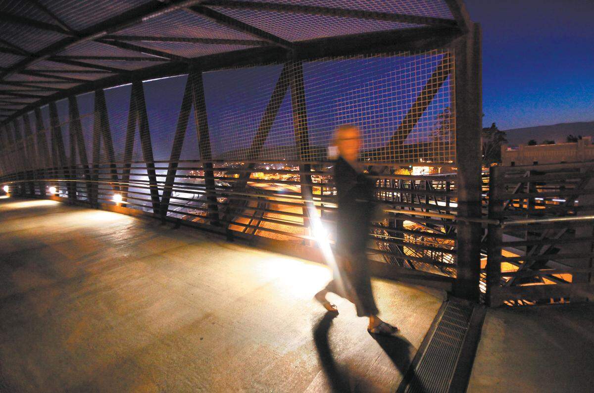A woman walks across the Jennifer Street Bridge at night, 10 years after the bodies of Rachel Newhouse and Aundria Crawford were discovered near Rex Krebs’ Davis Canyon home.
