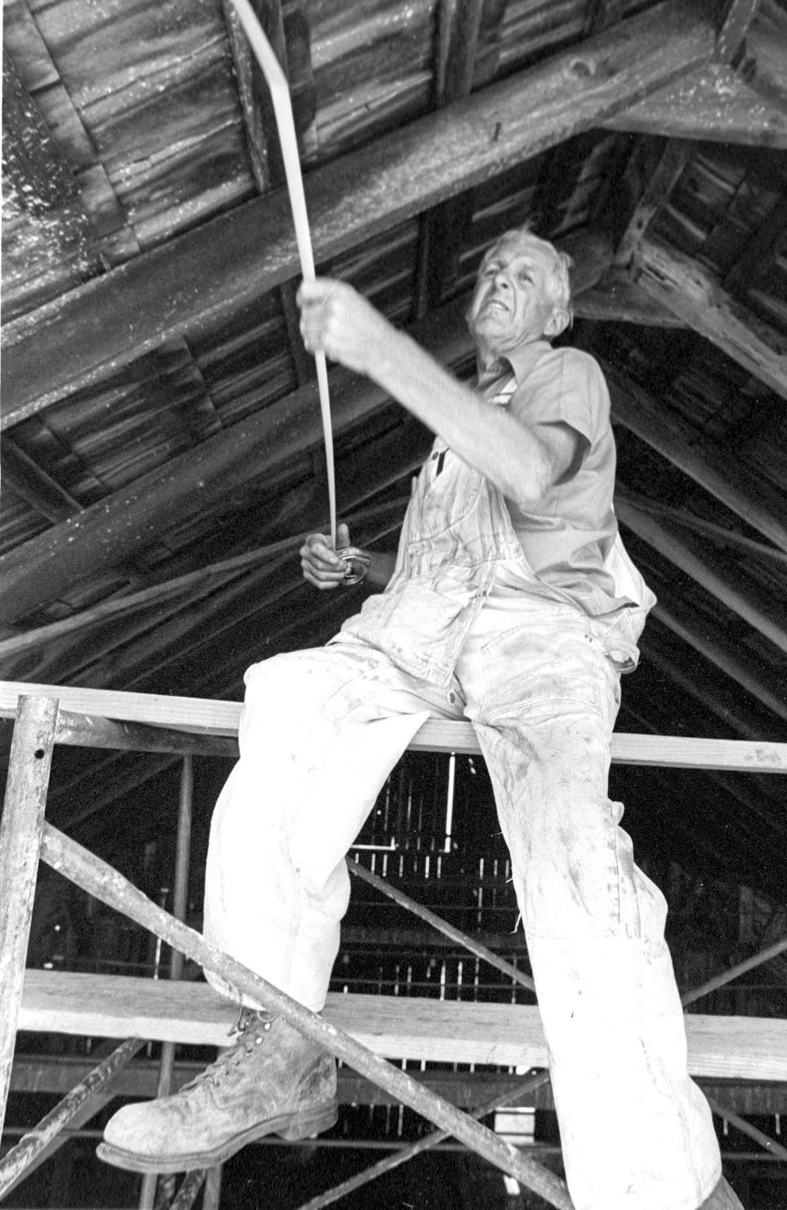 Danish-born carpenter Carl Nilsen takes a measurement during barn restoration. Efforts were underway on the almost century old dairy barn Aug. 17, 1982. The Mail Pouch Barn on Highway 1 at the base of Bishop Peak carried a chewing tobacco advertisement on the roof for many years. It was a popular subject for artists but when the roof deteriorated it was replaced and not repainted and the advertising campaign ended a few years later.