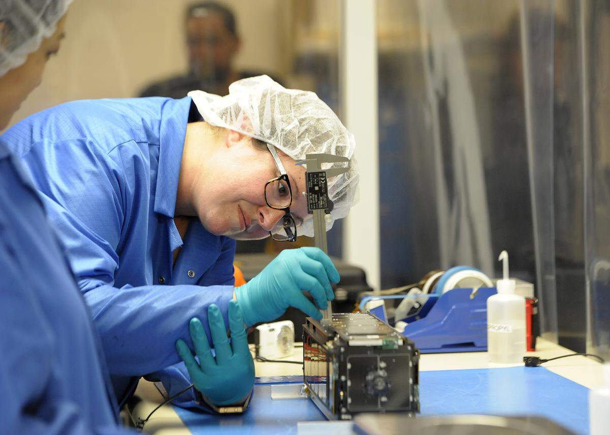 Aerospace engineer Alicia Johnstone with CubeSat at Cal Poly measures the Lightsail 2, a CubeSat meant to demonstrate solar sailing within low Earth orbit, developed by The Planetary Society.