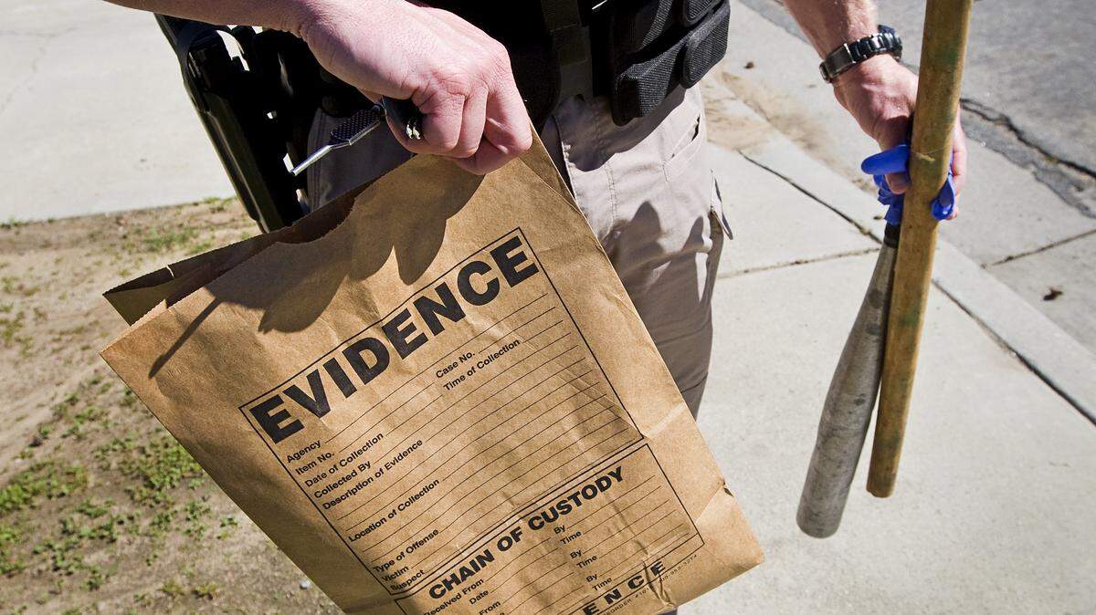 A member of the Sheriff’s Office Gang Task Force holds a bag of evidence, a bat and a wooden club seized from the home of a Paso Robles gang suspect during the serving of a search warrant in March.