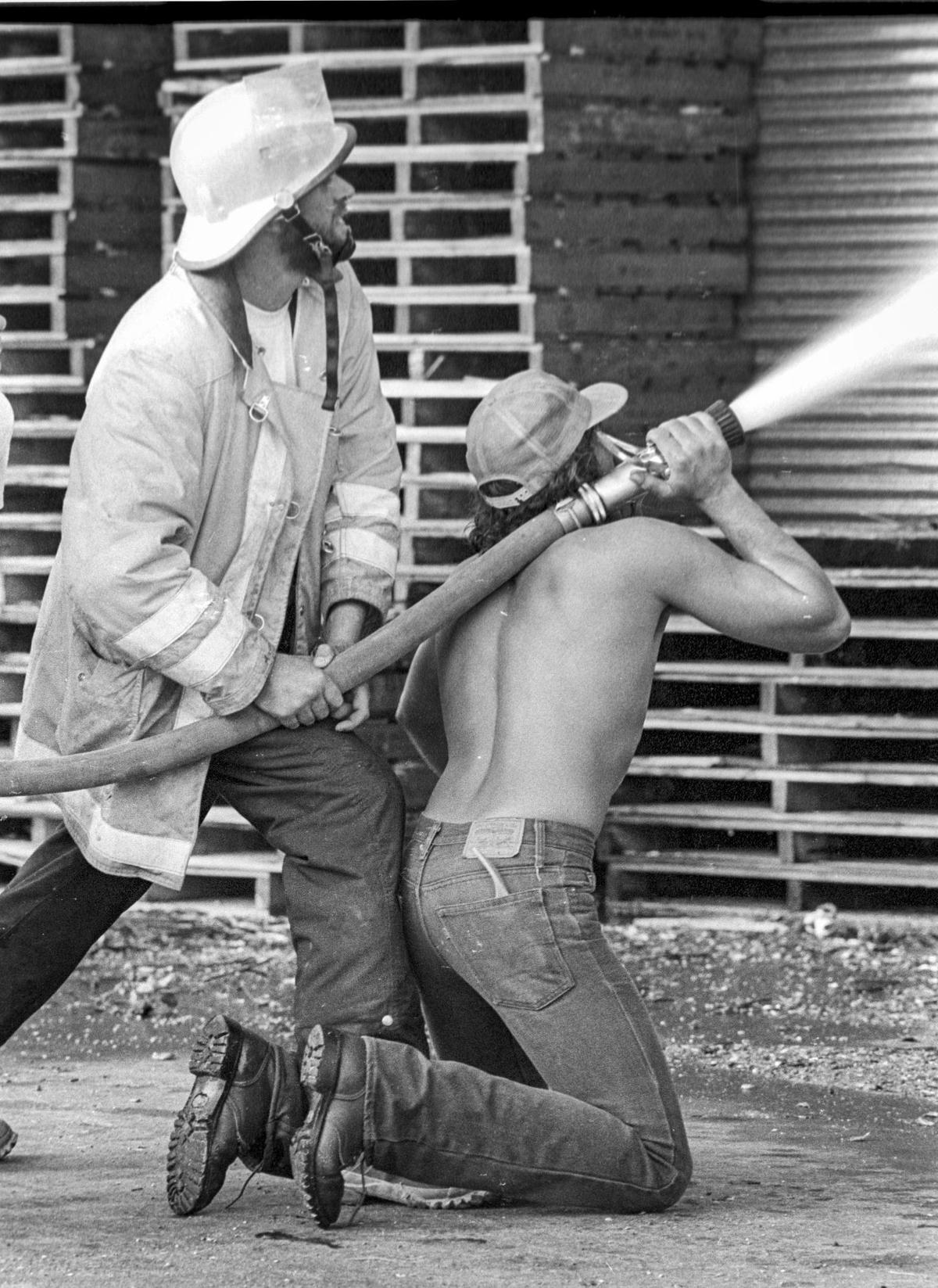 Templeton firefighter Tom Holoway and Chuck Manry spray water. Templeton Feed & Grain was damaged but survived an Aug. 24, 1979, fire. Spectators gathered along the old highway, now South Main Street, to watch firefighters work.