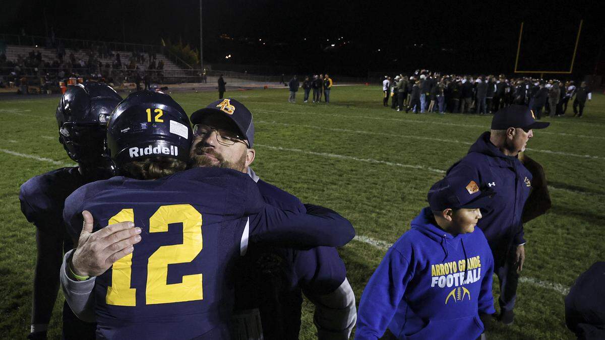 Head coach Stephen Field hugs quarterback Jacob Kreowski after the game as Ventura celebrates in the background. Ventura beat Arroyo Grande 35-28 in a high school state football championship semi-final on Dec. 5, 2025.
