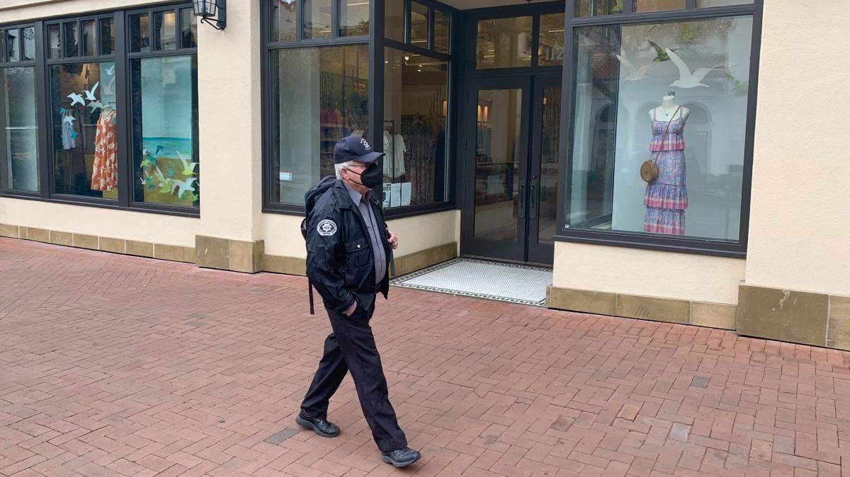 A private security guard walks along State Street in Santa Barbara on a recent morning. Property owners and city and county officials are considering a plan to expand private security for State Street.