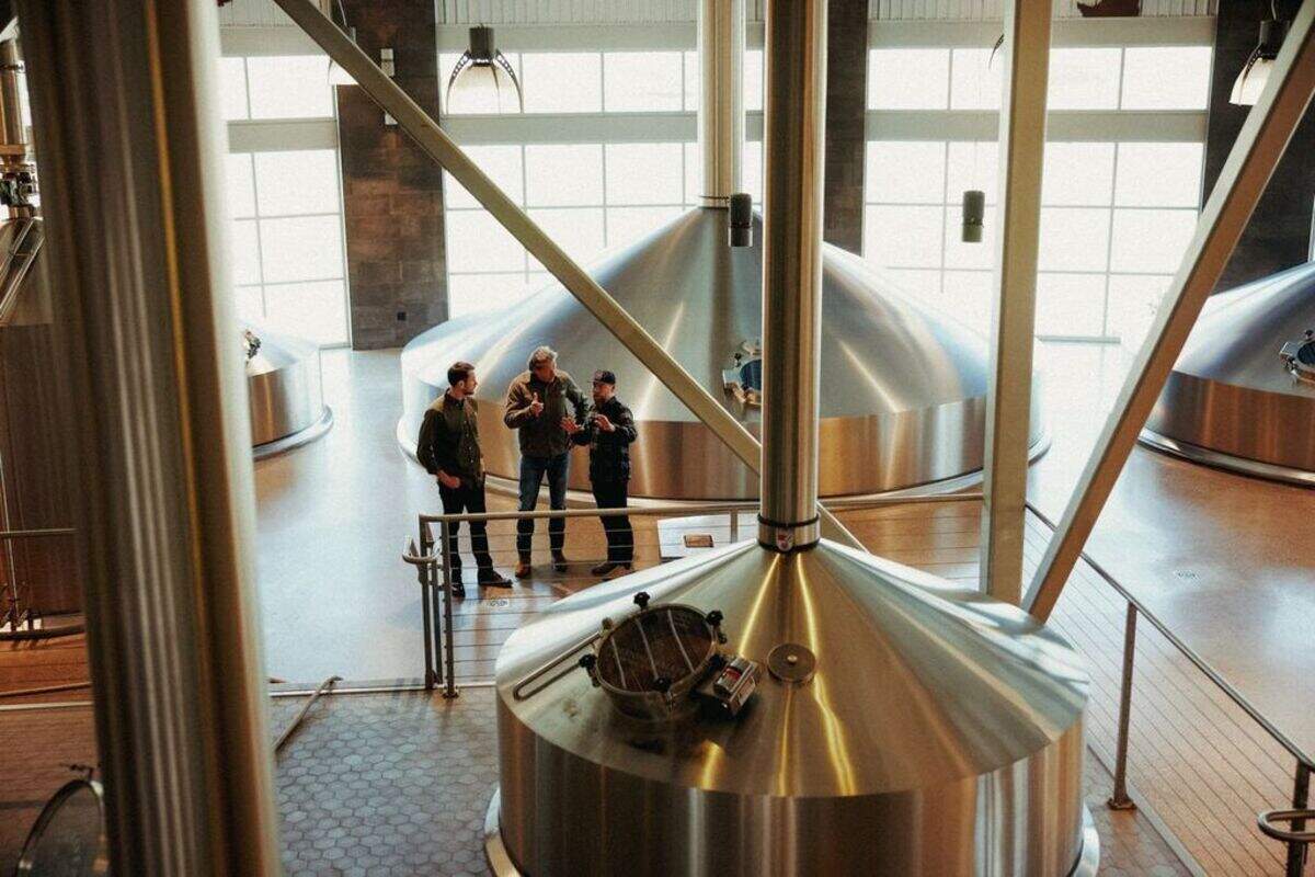 Firestone Walker Brewing Company’s CEO Nick Firestone, left, and co-founder David Walker consult with their brewmaster Matt Brynildson in a brewing area filled with large tanks at the company’s Paso Robles campus.