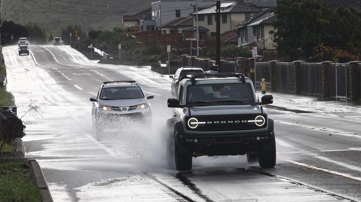 Cars splash through puddles on Orcutt Road near the Righetti Ranch development as rain continues Dec. 26, 2025.