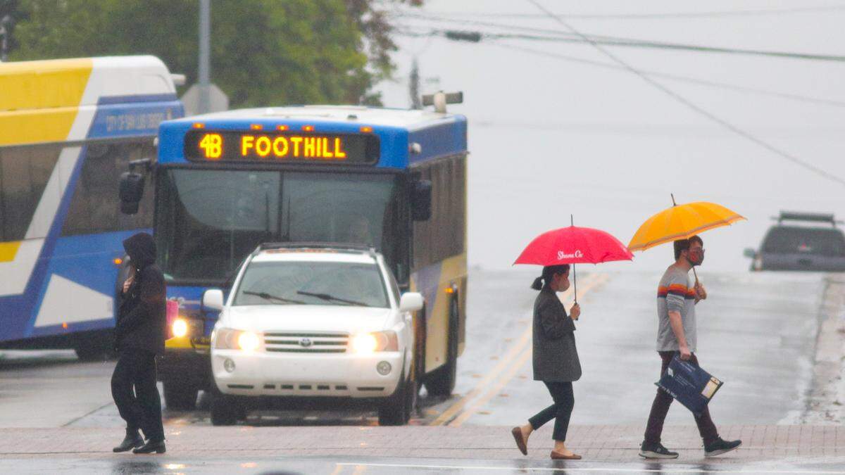 Pedestrians cross Osos Street near the San Luis Obispo City-County Library in San Luis Obispo on Monday, Nov. 7, 2022 as an early season storm moved through the area.