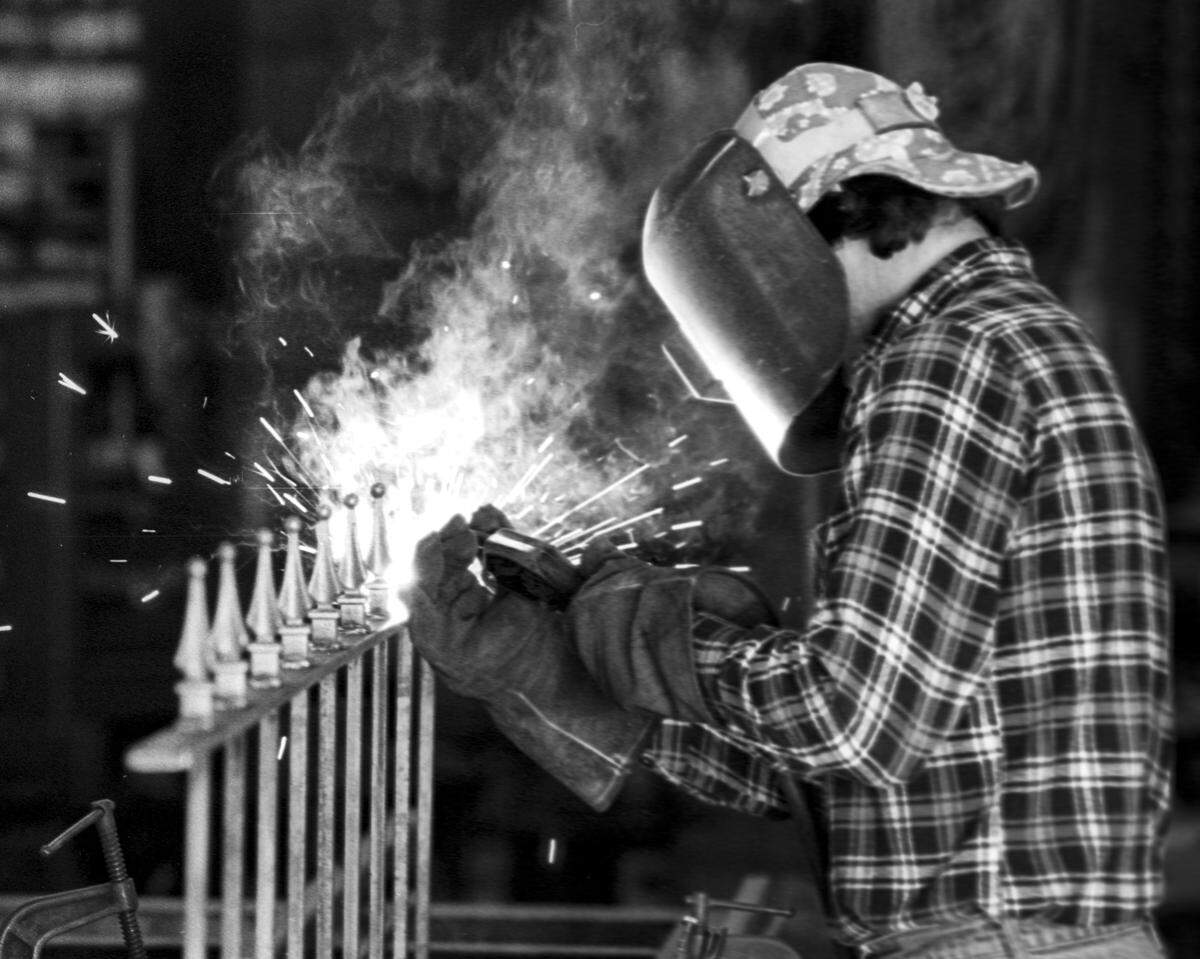 Sparks fly as Victor Rouse welds ornaments on a wrought iron fence. n Feb. 2, 1982.