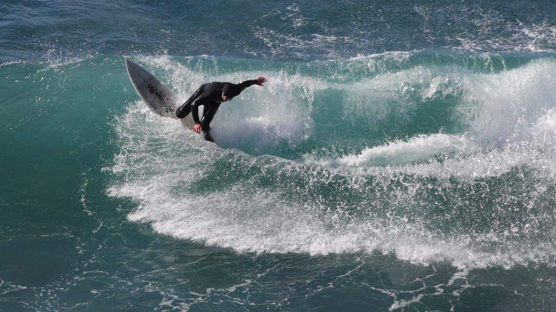 A surfer carves up a wave in the crystal, cold waters along the Big Sur coast.