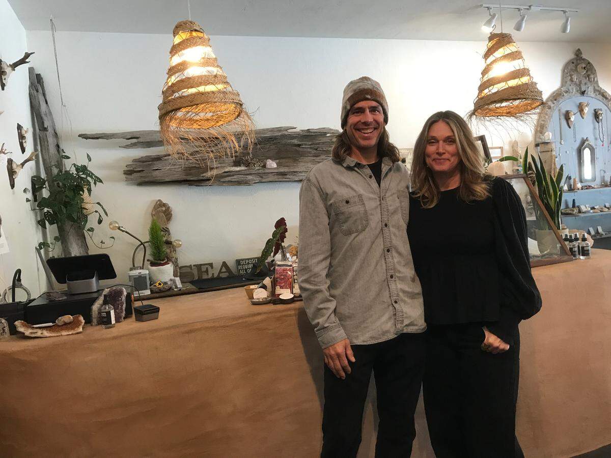 Sea + Green shop owners Jay Turton and his wife Becky Biskaduros stand in front of the front desk they built at their Cambria store.
