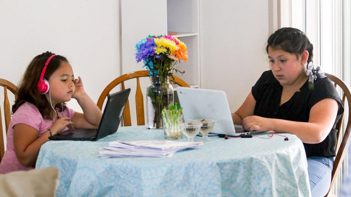 First-grader Adrien Peña and her sister, seventh-grader Scarlett Bannon work on their school assignments at home. Their mother, Vianna Mongeur, a single parent in Paso Robles, is juggling her job with the new role of homeschool teacher for her two kids.