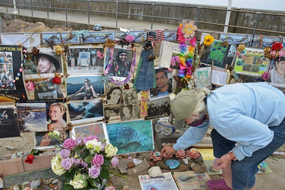 Jennifer Stafford of Santa Barbara places flowers and lights candles at the Conception dive boat memorial on the Santa Barbara Harbor breakwater Tuesday. 