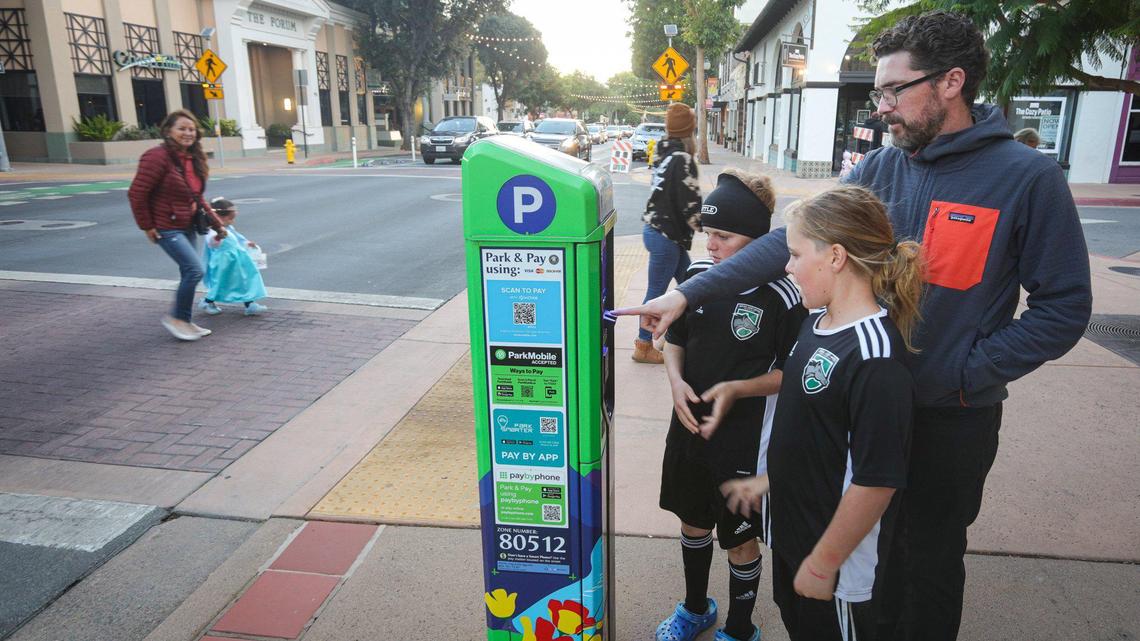 Jeff Andrews registers for parking on Marsh Street on Oct. 26, 2023, with help form kids Sebastian, left, and Emerson. Parking kiosks have replaced parking meters in San Luis Obispo’s downtown core, and parking fees are now paid via app or credit card.
