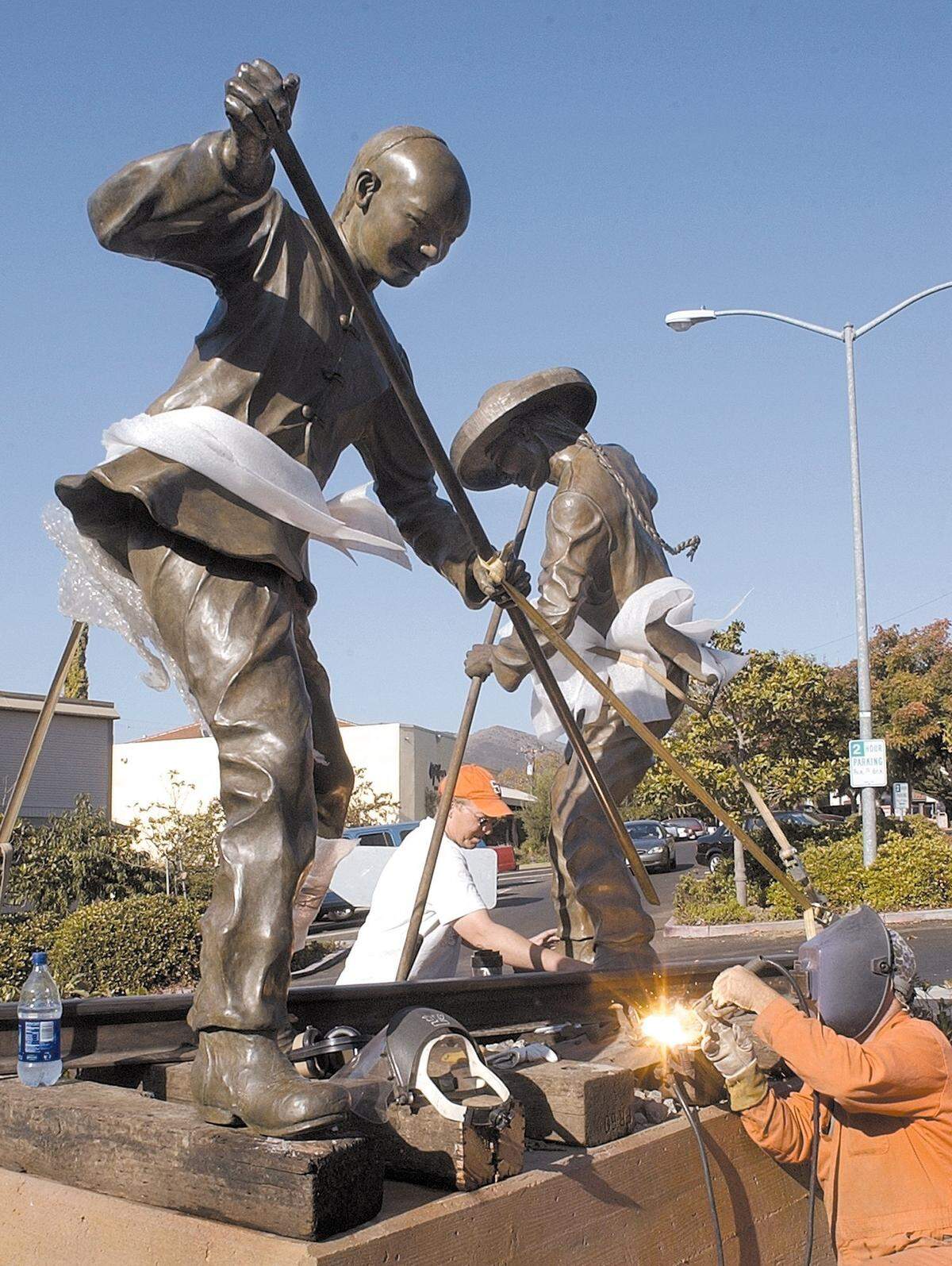 Allen Root welds and David Curry places concrete as a new sculpture is installed near the railroad station in San Luis Obispo, Oct. 17, 2002. Titled "Iron Road Pioneers" it is by Elizabeth MacQueen, and it honors the Chinese contribution to the economy of California through their construction of railroads.