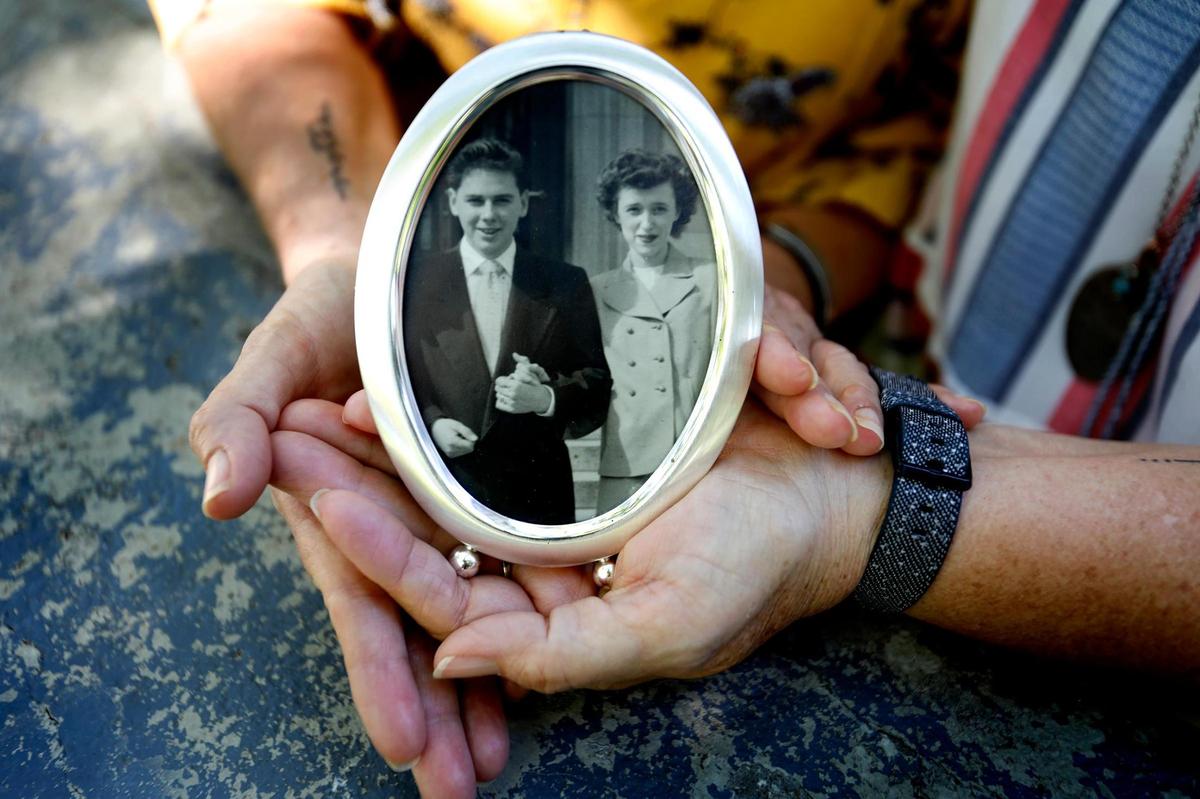 Lori Head and Melinda Luce show off an old photo of their parents. Their mother, Margery McGoff, died from coronavirus in July.