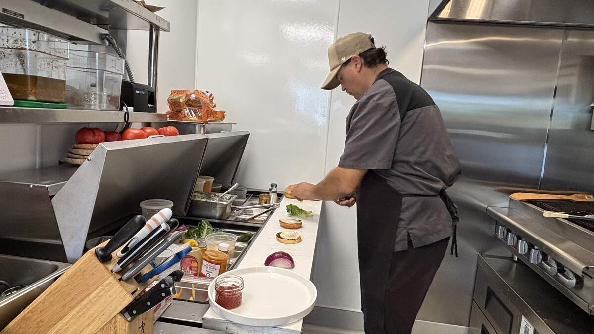 Melo Mela Kitchen Chef Gregg Wangard assembles the wagyu burger with mayonnaise, tomato, pickles, lettuce and cheese on a brioche bun from Back Porch Bakery, seen here on June 25, 2026.