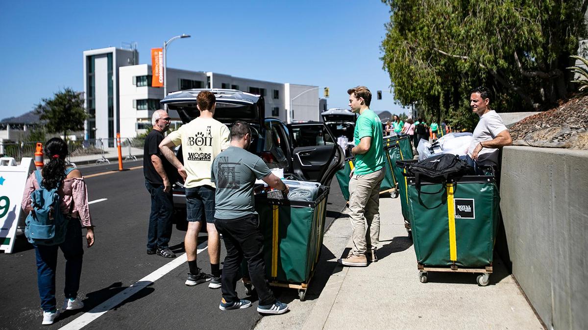 Cal Poly students in green help incoming freshmen and their families unload their belongings into green bins on Tuesday, Sept. 13, 2022, as the new students moved onto campus. The loading zone began at Grand Avenue and snaked around to the top level of the parking structure at the Performing Arts Center. After the new students move in, they’ll join their WOW groups on Wednesday evening for four days of orientation before classes begin next week.