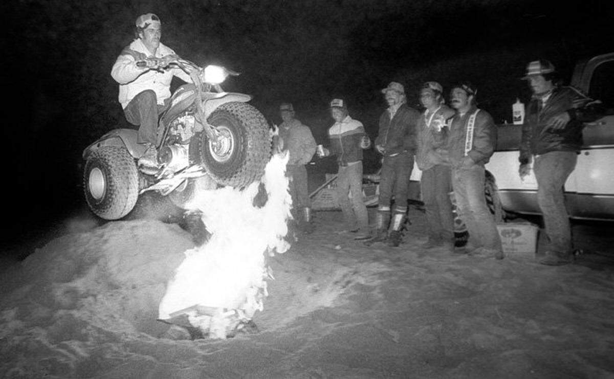 Joe Souza of Visalia soars across an open fire pit on his sand cycle as his buddies watch during Labor Day weekend 1982.