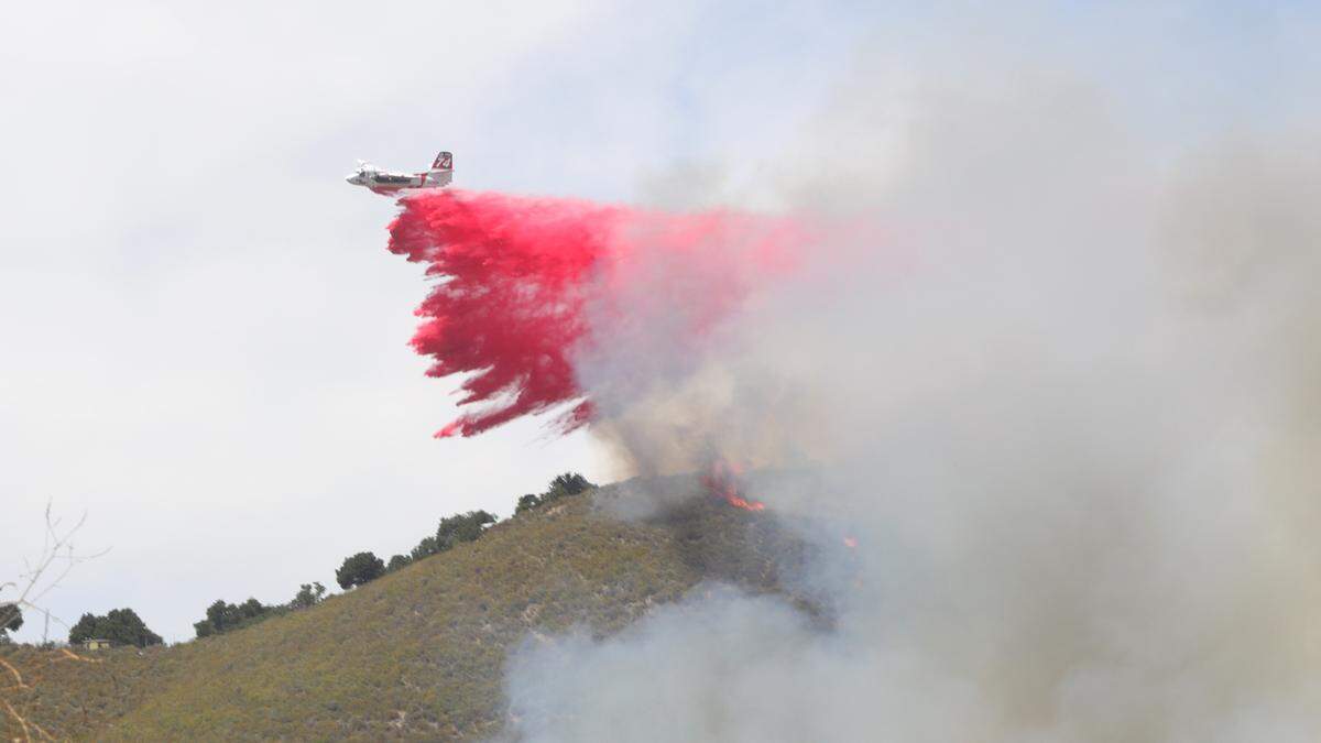 An air tanker drops retardant Monday on a fire burning a hillside along Highway 101 near the Avila Beach Drive exit.