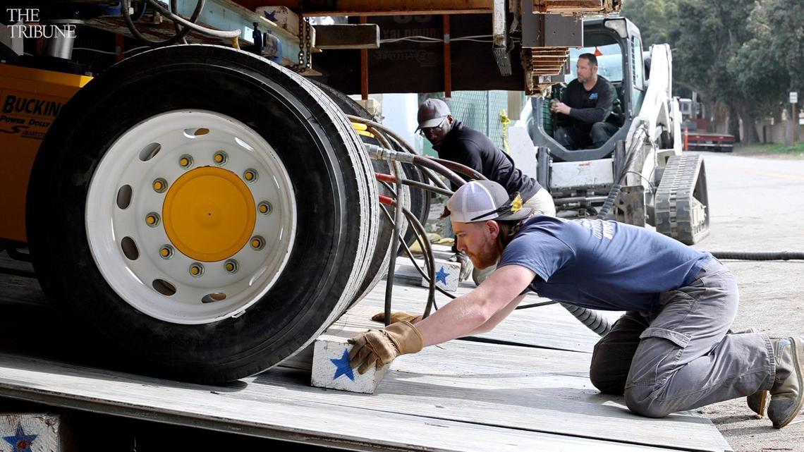 Workers with Scott Heavy Movers block wheels as Sebastian’s store is returned to its old location on a new foundation in San Simeon.