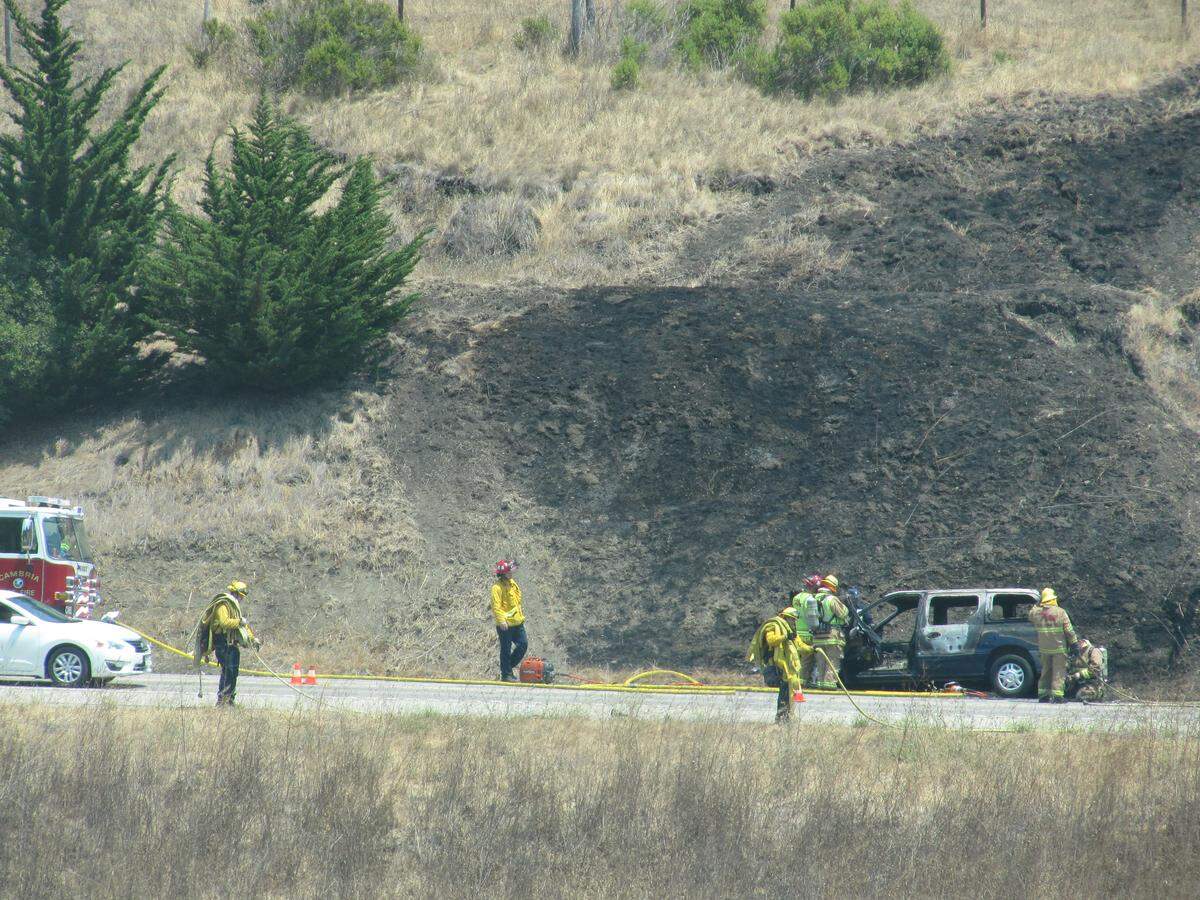 Firefighters mop up after a van fire scorched roadside grass along Highway 1 in Cambria on Sunday, July 29, 2018.