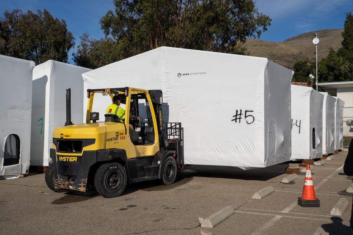 A forklift operator places a 3D-printed home into its storage spot at the Welcome Home Village project site on Friday, Nov. 21, 2025. The homes were produced at a facility in Gardena and shipped to San Luis Obispo in late 2025.