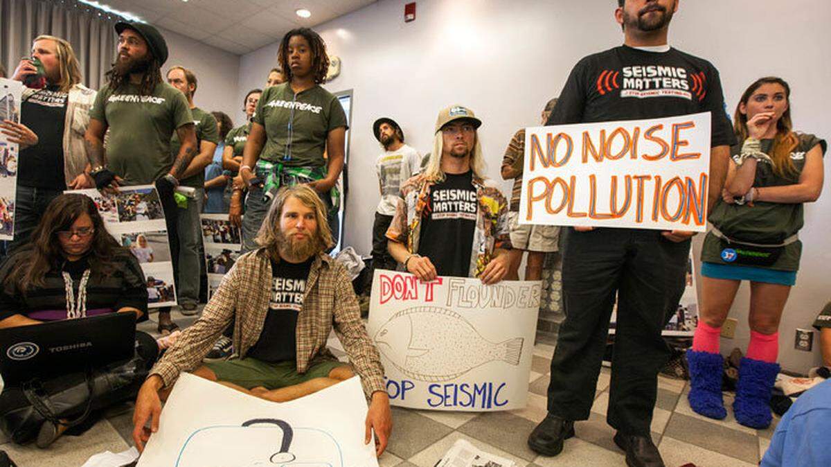 Environmentalists Cody Riechers, sitting left, and Connor Chicott, middle, hold up signs during a California Coastal Commission meeting in Santa Monica on Wednesday, Nov. 14, 2012.