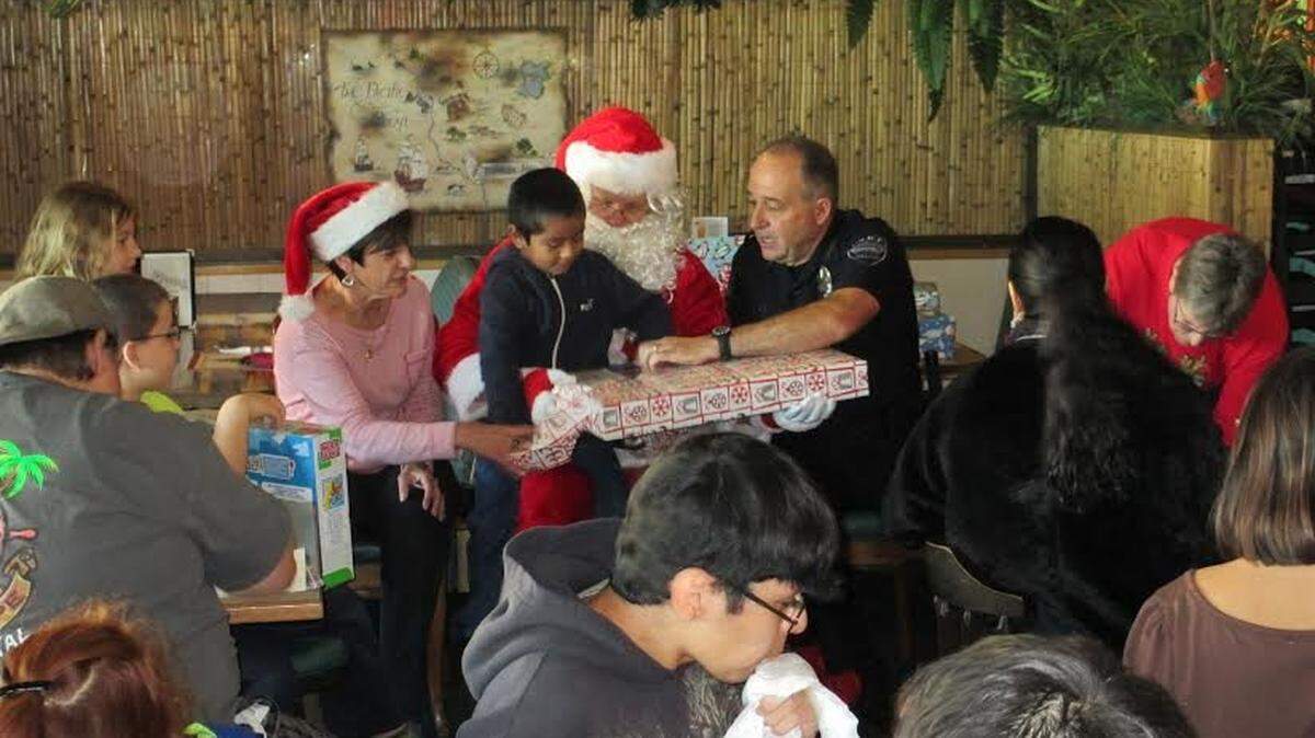 Arroyo Grande police Chief Steve Annibali visits with Santa Claus and participants in the Santa Cop program at Quarterdeck restaurant in 2014.