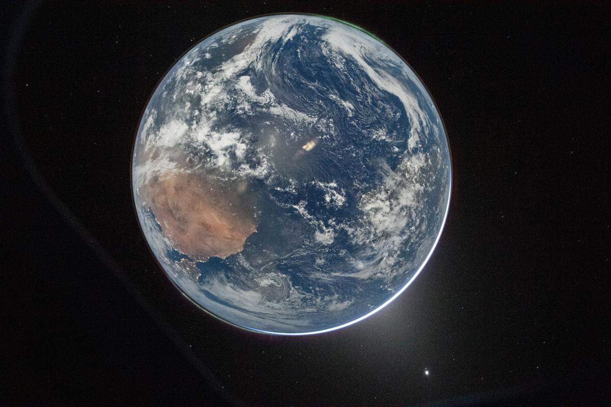 NASA astronaut and Artemis II Commander Reid Wiseman took this picture of Earth from the Orion spacecraft’s window on April 2, 2026, after completing the translunar injection burn. The green glow of the Northern Lights is visible along the upper edge.