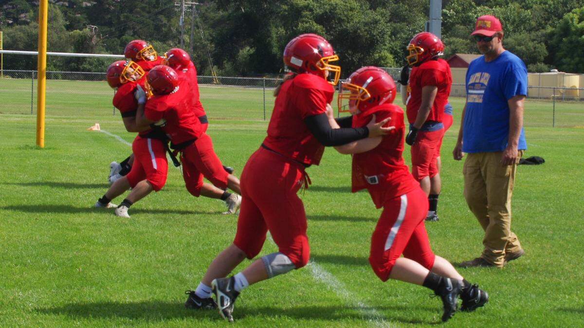 The Coast Union High School football team practices on Friday, Aug. 11, 2023. Emily Reed, left foreground, was engaged in blocking drills with Rye Whitbill, under the watchful eye of volunteer coach Bryon Haanen.