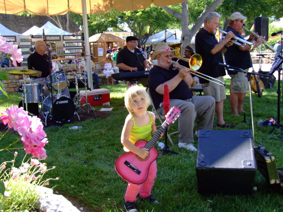A confident young Ella Nelson picks out chords alongside a band playing (smartly, in the shade) at the 2011 Mid-State Fair.