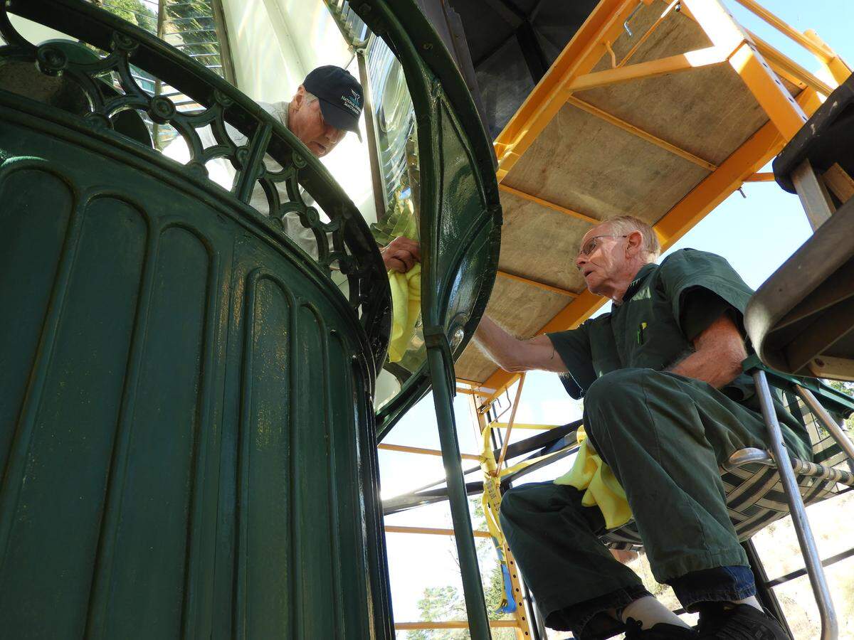 Phil Adams, left, and Jim Woodward polish a prism inside the Piedras Blancas Lighthouse lens during a cleaning in 2018.