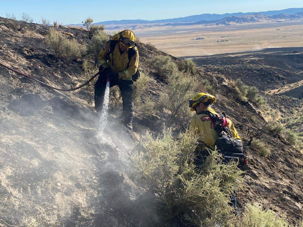 Firefighters douse hot spots while mopping up a grass fire that burned 90 acres in California Valley in July.