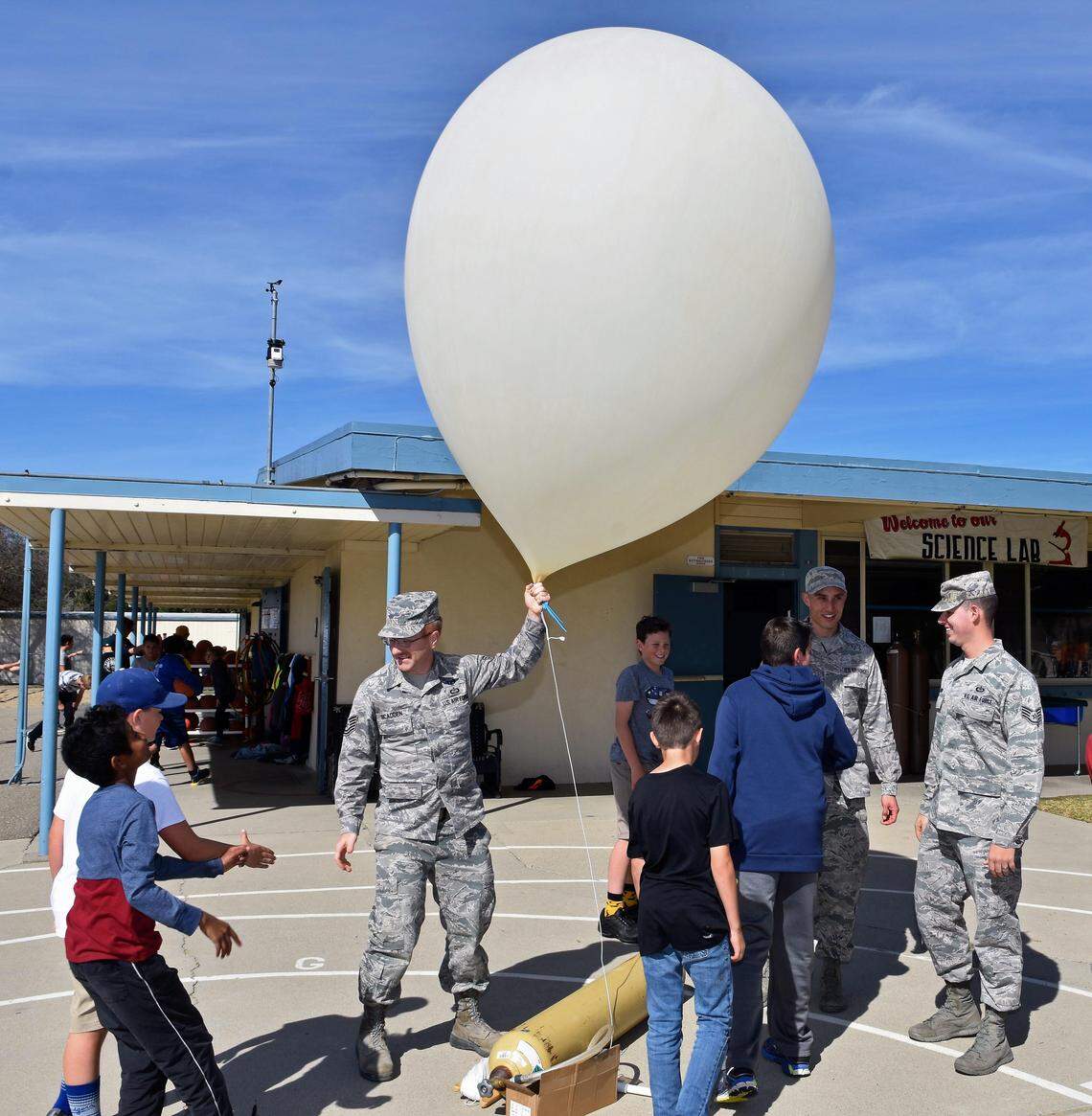 U.S. Air Force meteorologists launch a weather balloon at Branch Elementary School in Arroyo Grande. Technical Sgt. Scadden is holding the balloon, while Staff Sgts. Garza (left) and Bowen look on.