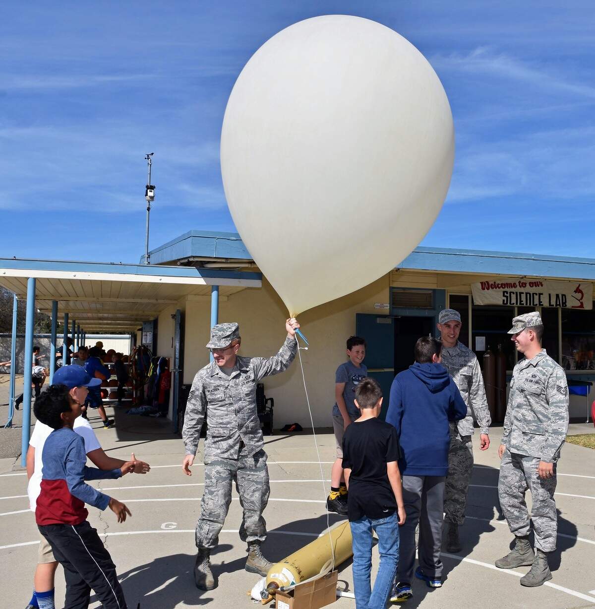 U.S. Air Force meteorologists launch a weather balloon at Branch Elementary School in Arroyo Grande. Technical Sgt. Scadden is holding the balloon, while Staff Sgts. Garza (left) and Bowen look on.