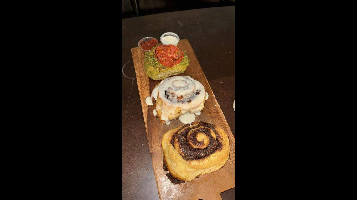 A pesto roll, a classic cinnamon roll and a plain cinnamon roll are displayed as part of Roll’d SLO’s menu.