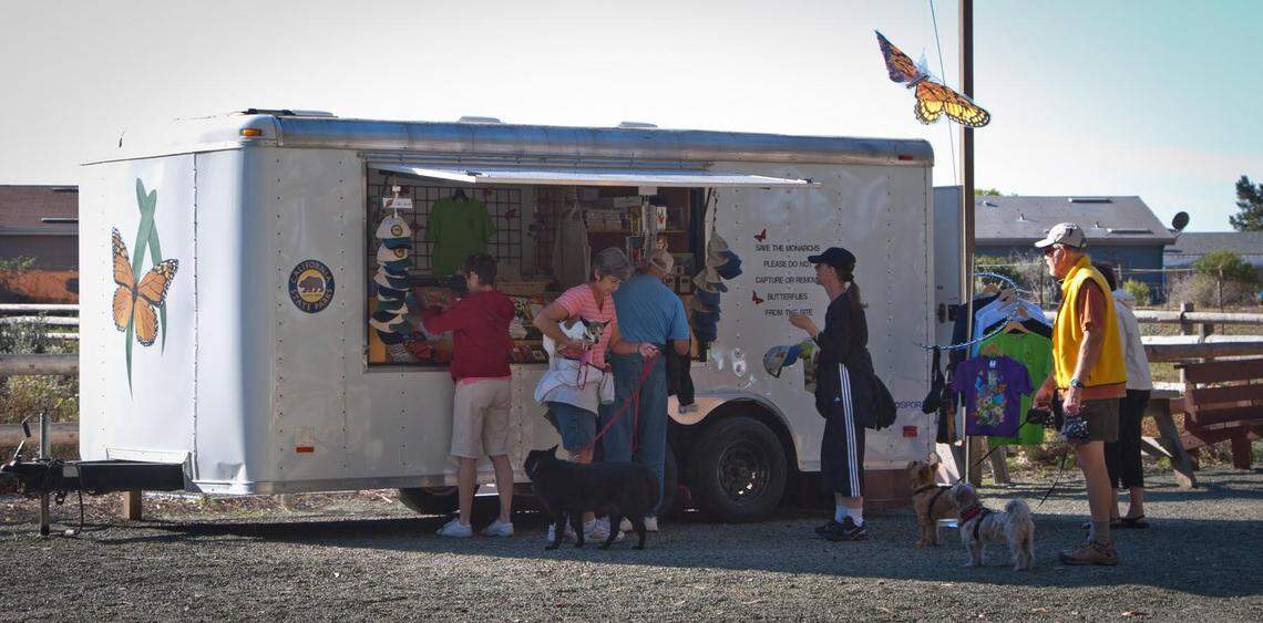 Vistitors to the Monarch Butterfly Grove check out the souvenirs available for purchase in Central Coast State Parks Association’s old trailer. The group is fundraising for a new one this season.