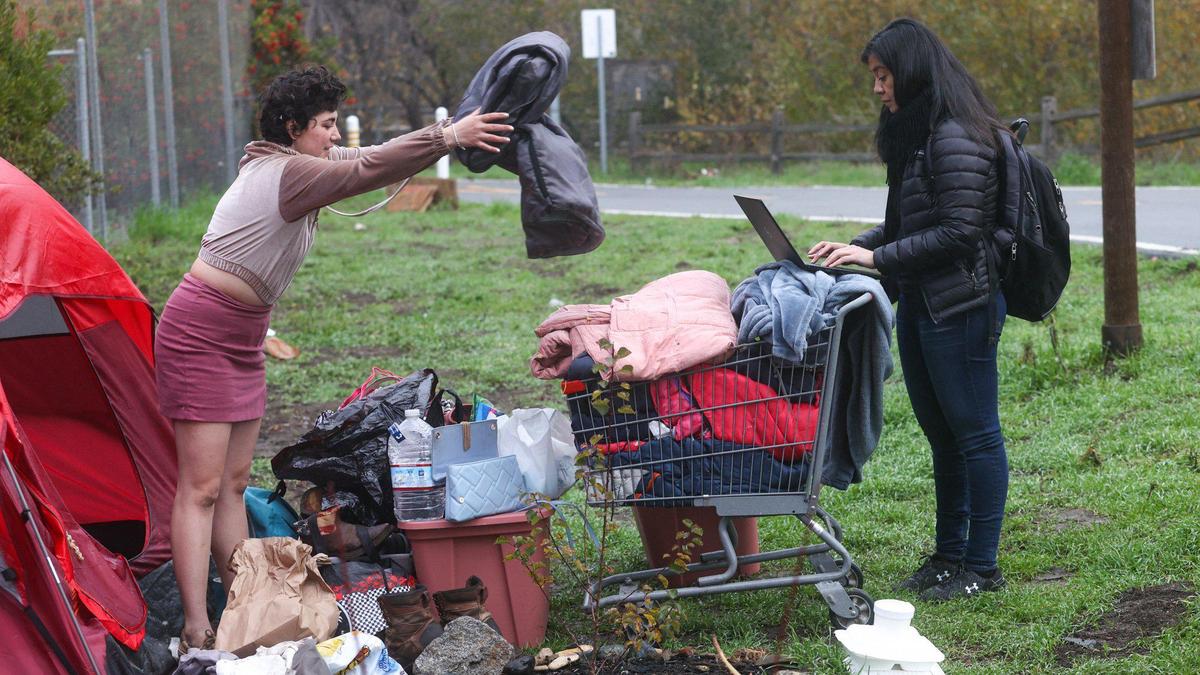 Ashlynn Miles throws her blankets into a basket as she talks to Sasha Aguilar, an attorney with California Rural Legal Assistance, on Jan. 6, 2022, as Miles is evicted from a homeless encampment on the Bob Jones City-to-the-Sea Bike Trail near Prado Road in San Luis Obispo.