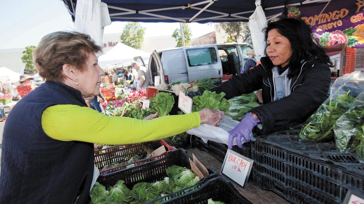 Jo Siemsen of San Luis Obispo purchases butter lettuce from Shirley Hinzo of Arroyo Grande’s Domingo Farms at the Saturday morning farmers market held in San Luis Obispo in 2015.