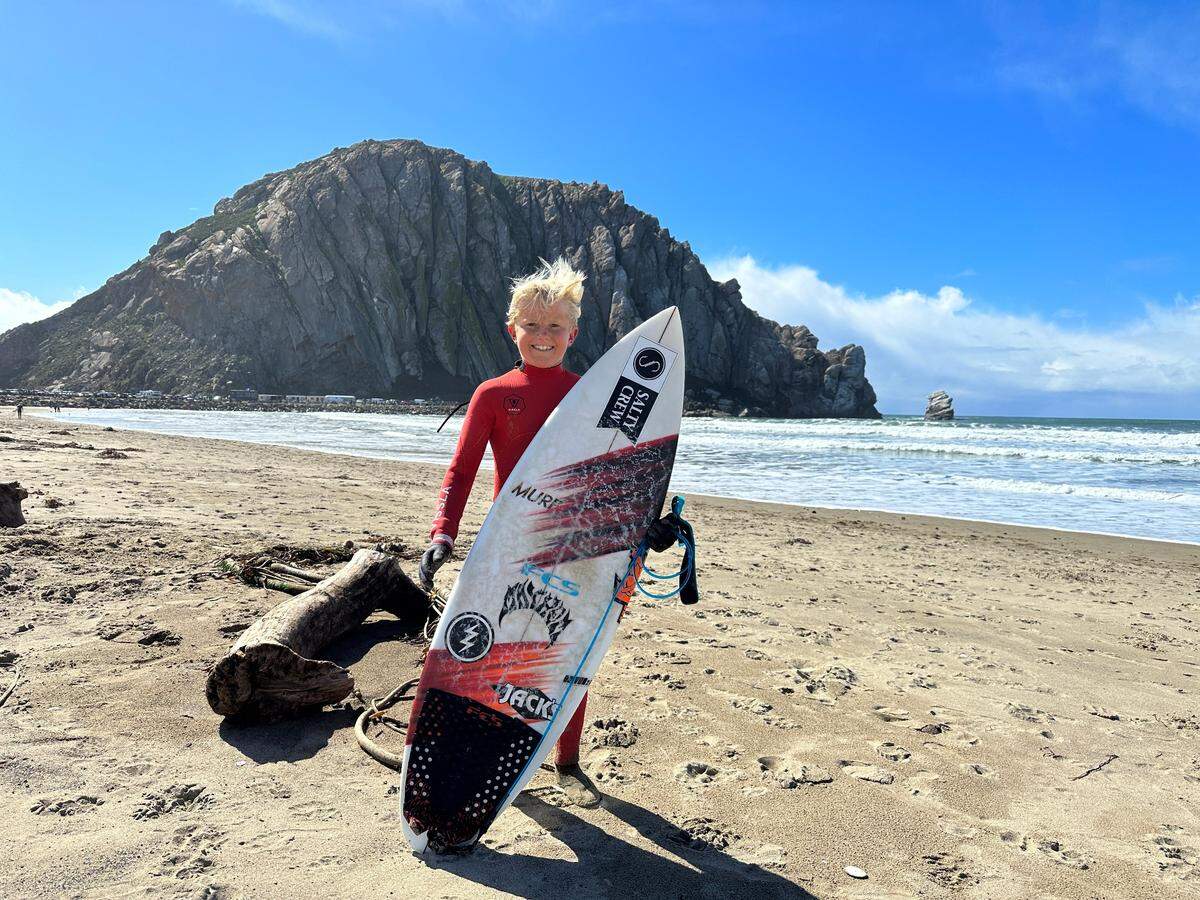 Kian Walla, 11, of San Clemente prepares to surf in Morro Bay on Feb. 23, 2023 — a day that began with snow on the mountains overlooking the ocean.