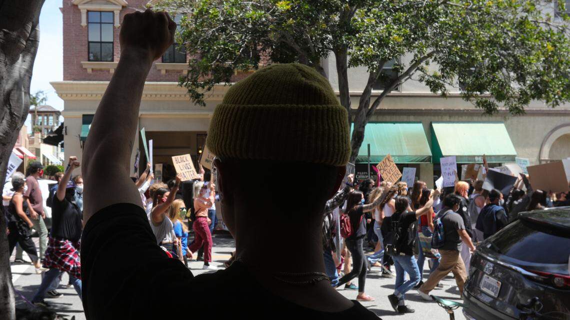Chris Limon, owner of a men’s clothing boutique Passport on Monterey Street, signals solidarity with marchers during the June 1, 2020, protest that drew more than 3,000 people downtown.