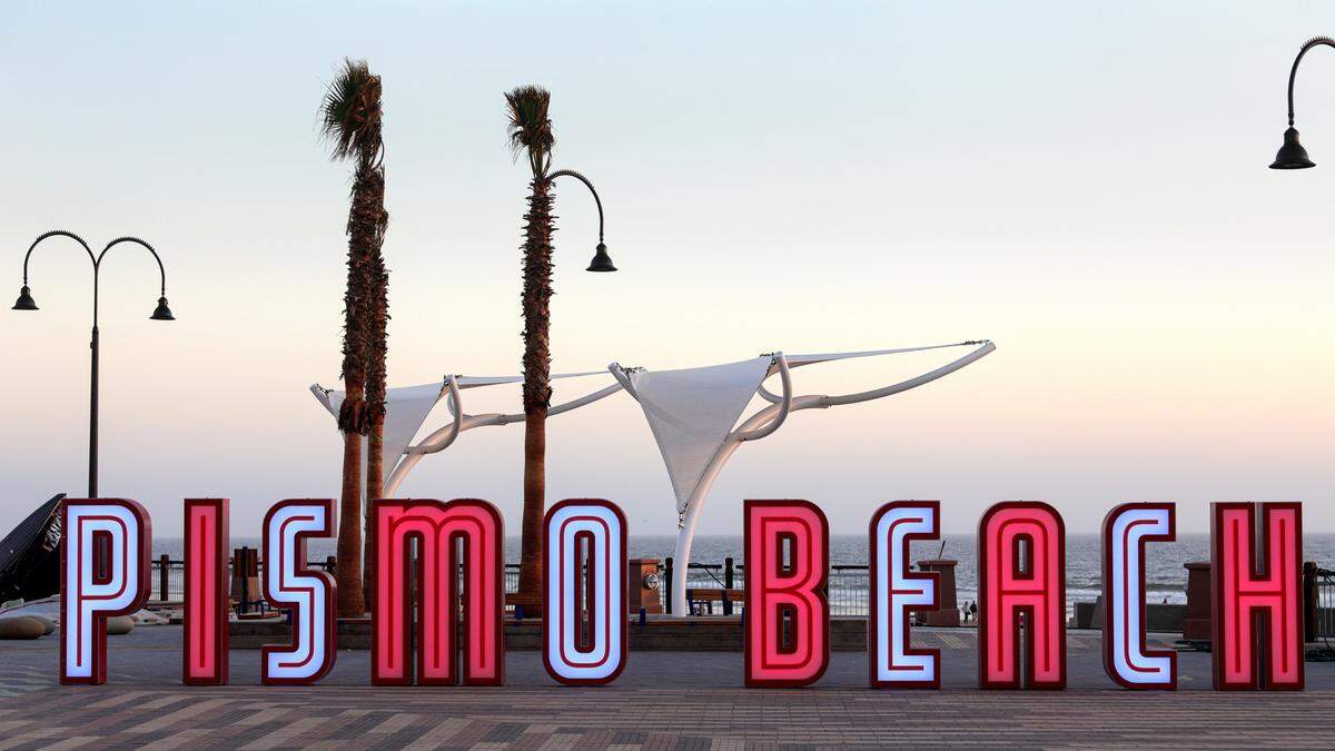 A light-up sign near the Pismo Beach pier spells out “Pismo Beach.” 