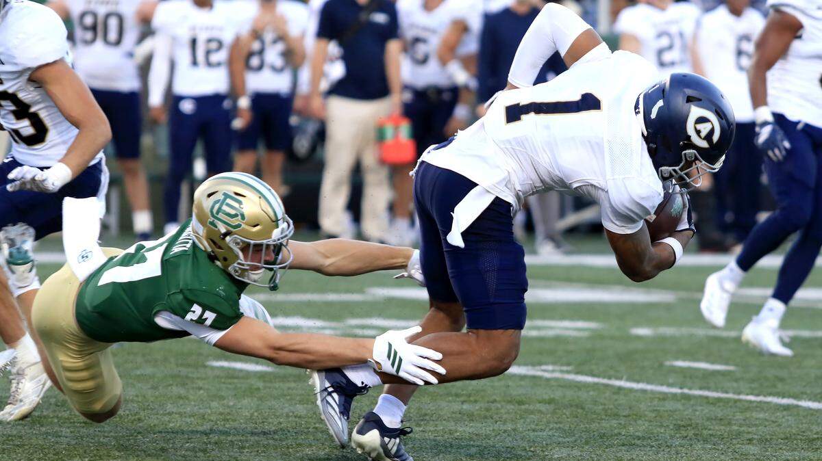 The Cal Poly Mustangs’ Hudson Giarritta dives to tackle the UC Davis Aggies’ Khalani Riddick in a college football game Saturday at Mustang Memorial Stadium in San Luis Obispo.