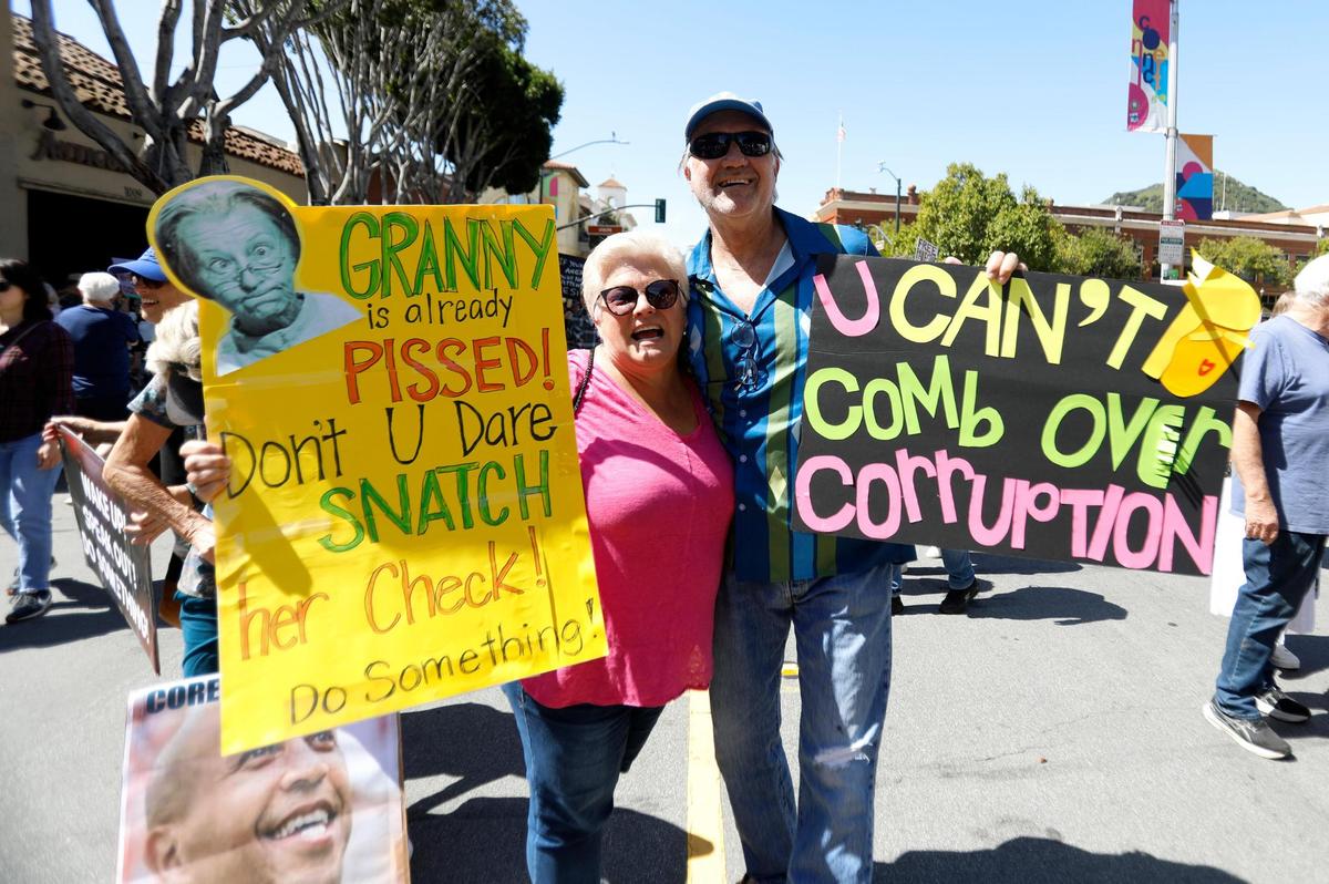 LMUSD Board President Colleen Martin holds her sign and friend Mike Miller, of Arroyo Grande joins her. Thousands of people gathers at San Luis Obispo Superior Court in California as part of the “Hands Off!” rally to protest President Donald Trump and his advisor Elon Musk.