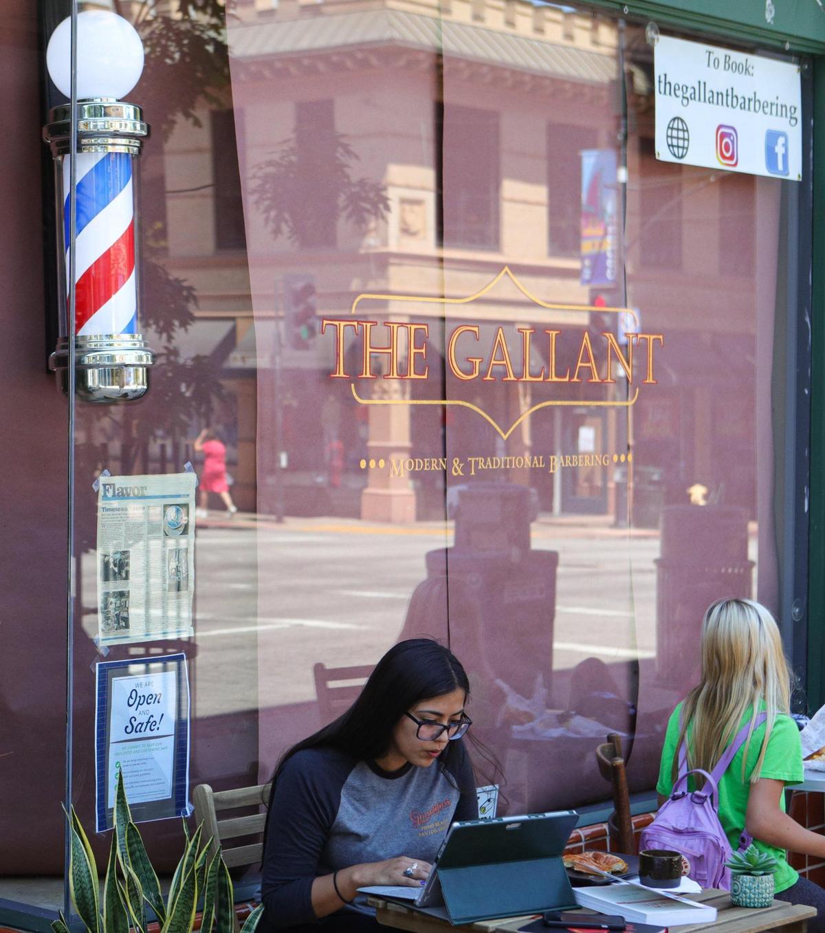 Cuesta College summer school student Dana Leyva completes work next to Kin Coffee coffee shop. Behind her, barbershops like The Gallant on Higuera Street were ordered to close due to coronavirus restrictions.