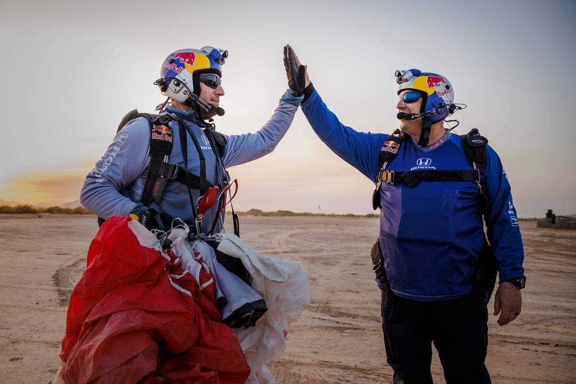 Pilots Luke Aikinsm, right, and Andy Farrington share a high five on the ground after their daredevil plane swap attempt in Eloy, Arizona, on April 24, 2022.