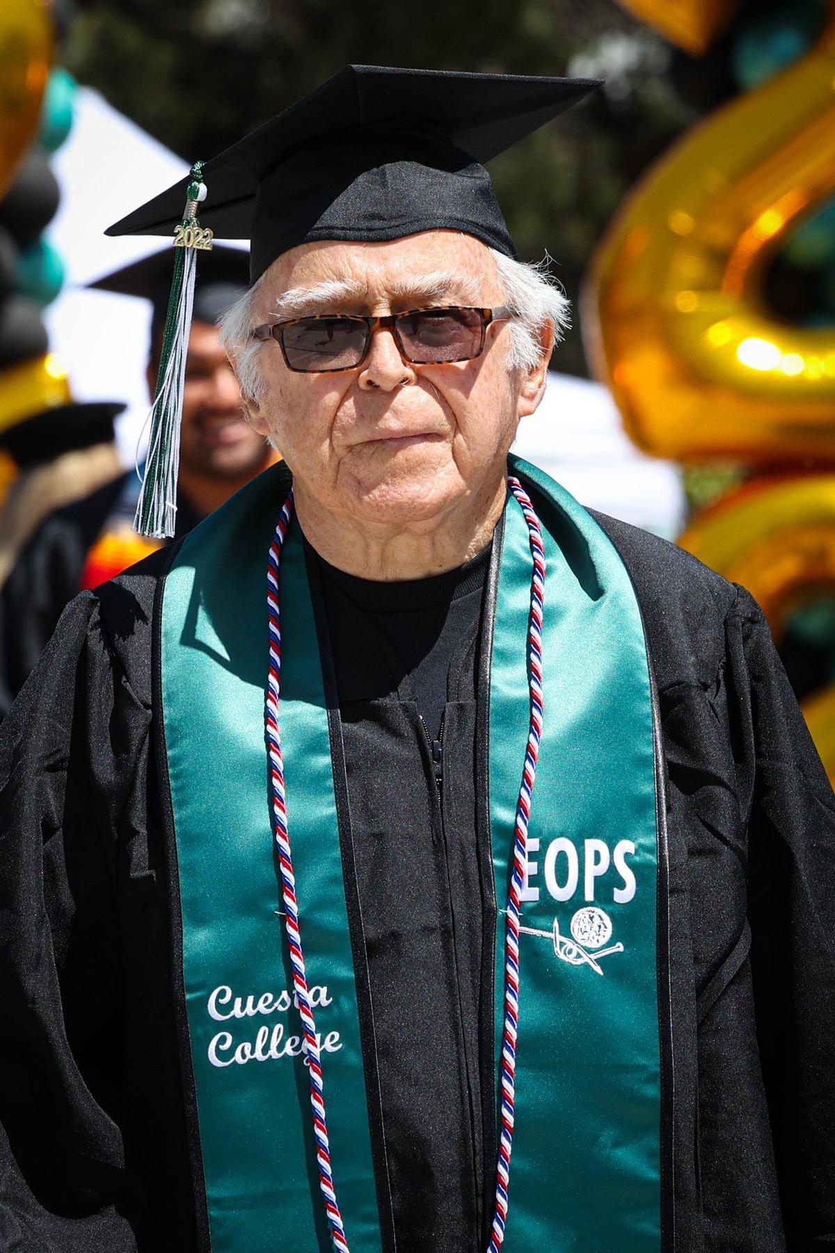 Don Bukowski walks as Cuesta College held the 57th Commencement Ceremony as family drives nearby a drive through.
