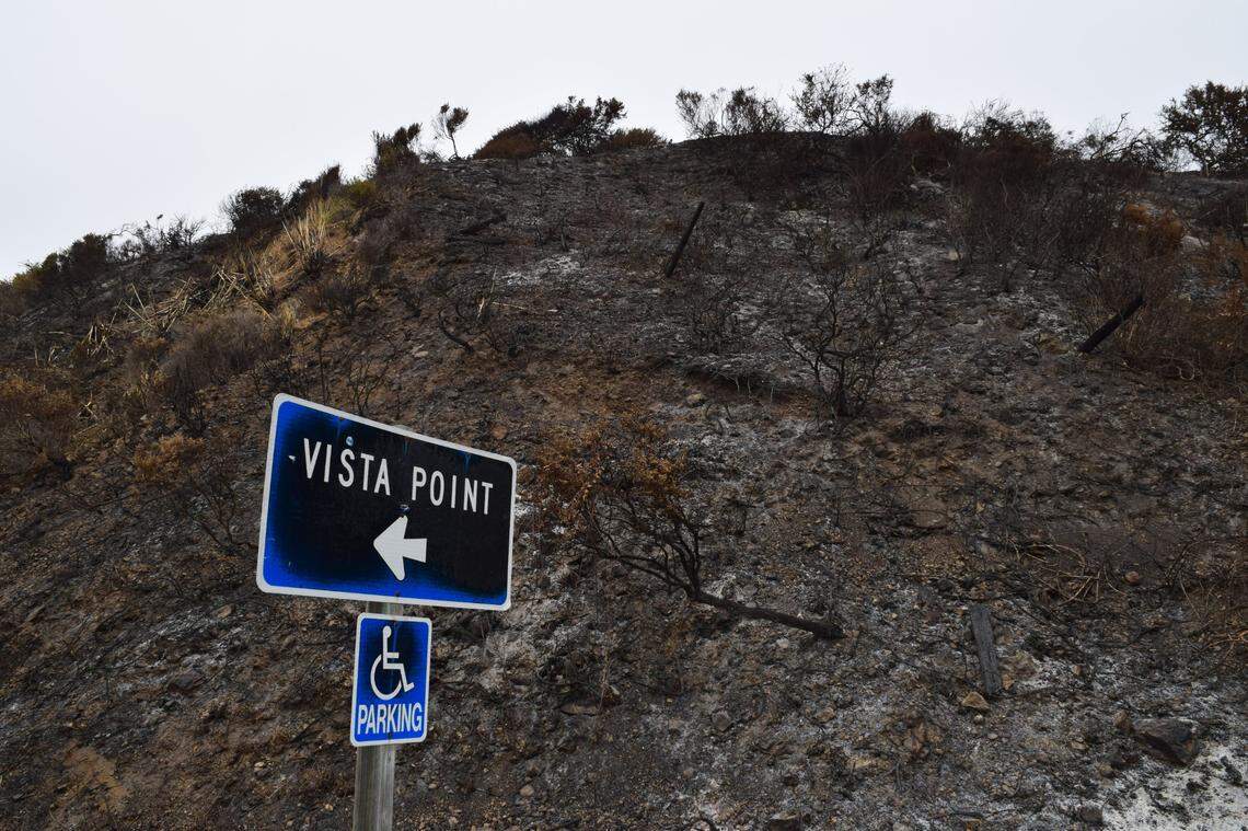 A charred sign pointing to a vista point rests along Highway 1. The Dolan Fire has burned more than 21,000 acres in the Los Padres National Forest’s Ventana Wildneress and cut off access to the popular tourist route.