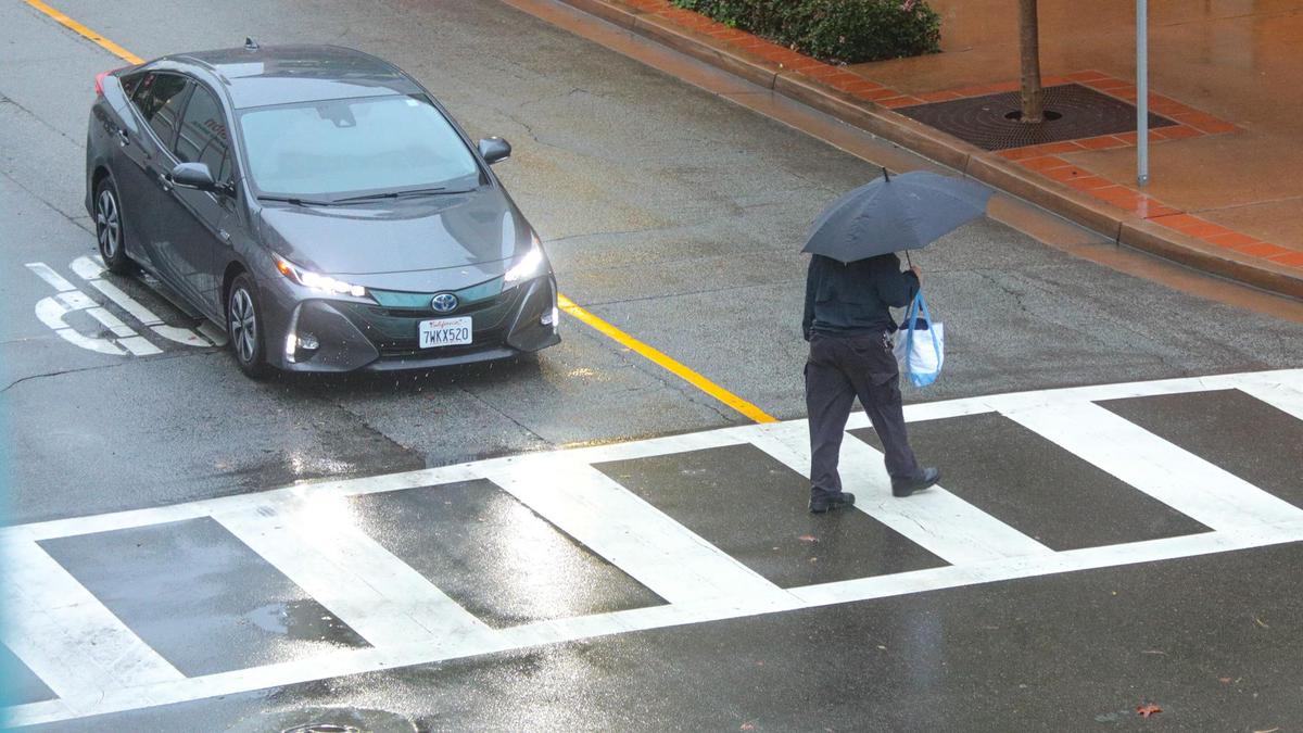 A pedestrian crosses Palm street as rain continued to fall in downtown San Luis Obispo on Tuesday, Dec. 14, 2021.