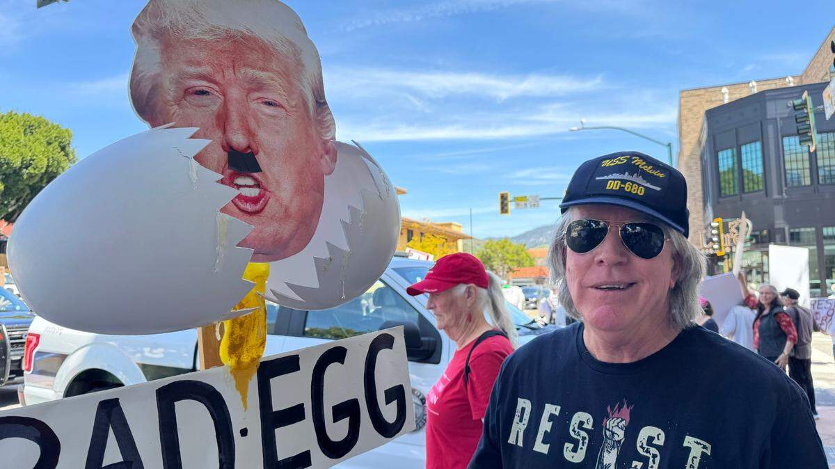 Mark Turner of Atascadero stands beside his “bad egg” poster at the “hands-off” rally in downtown San Luis Obispo on April 5, 2025.